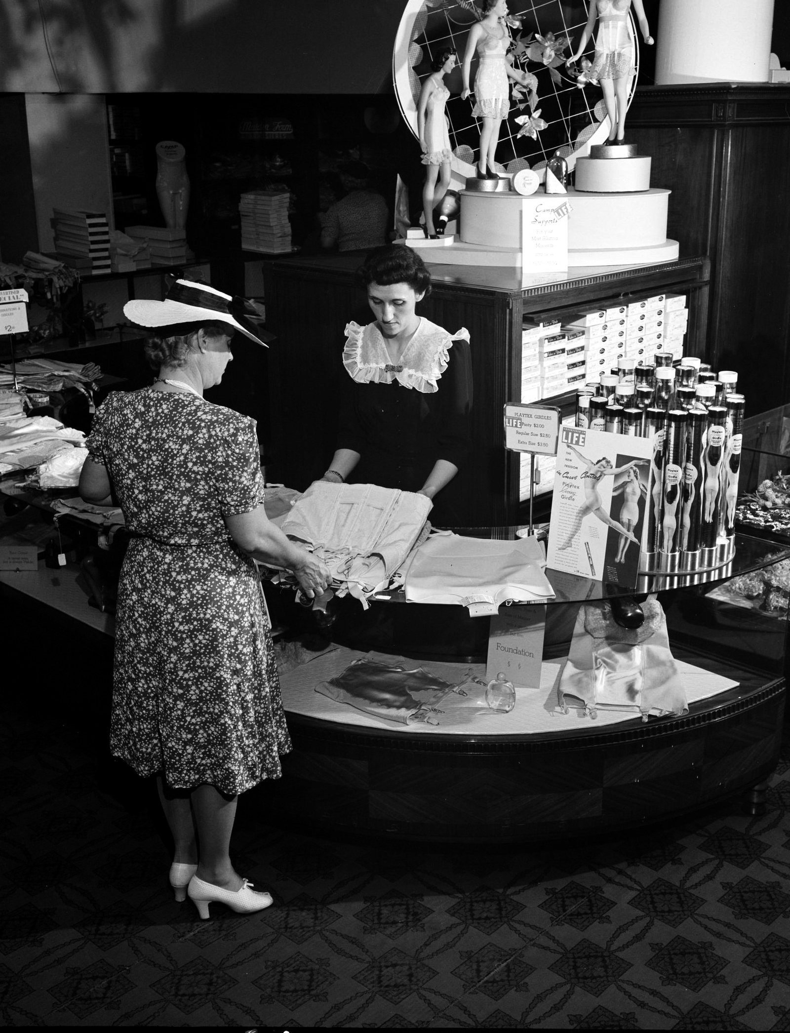 A shopper at the counter of a department store corset department.