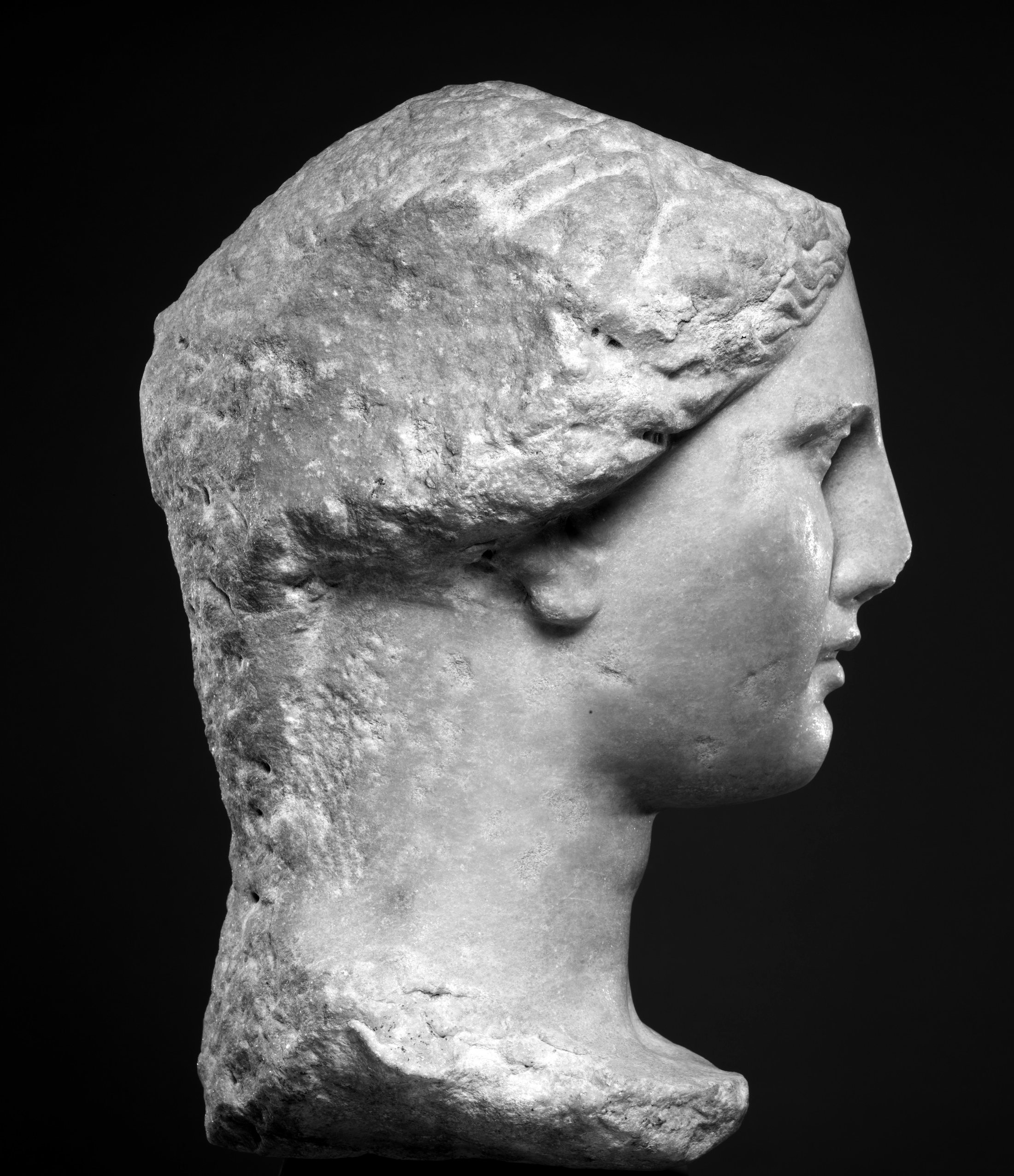 A marble head of a woman in profile against black.
