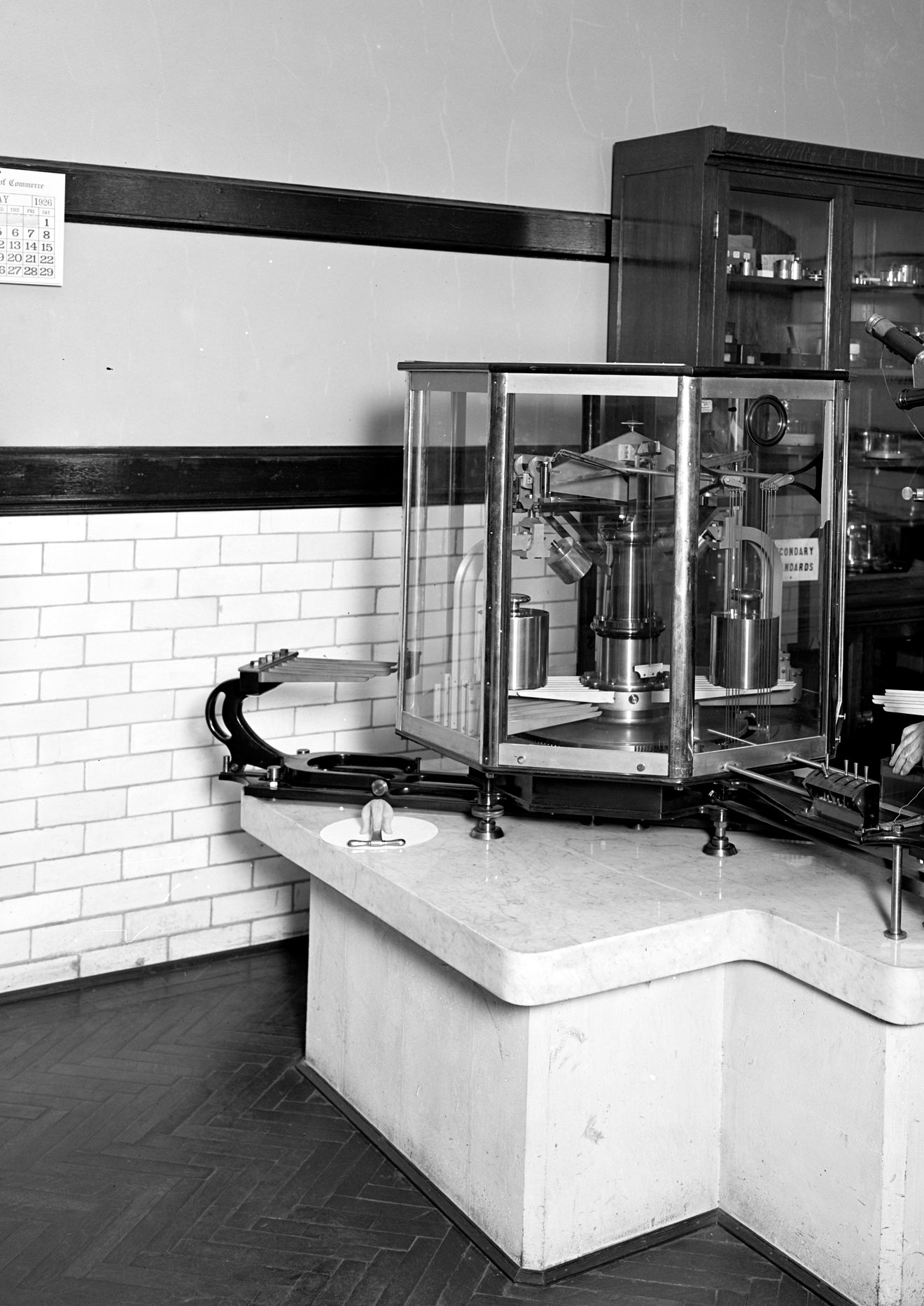 A precision balance in a glass case on a stone pier at the Bureau of Standards.