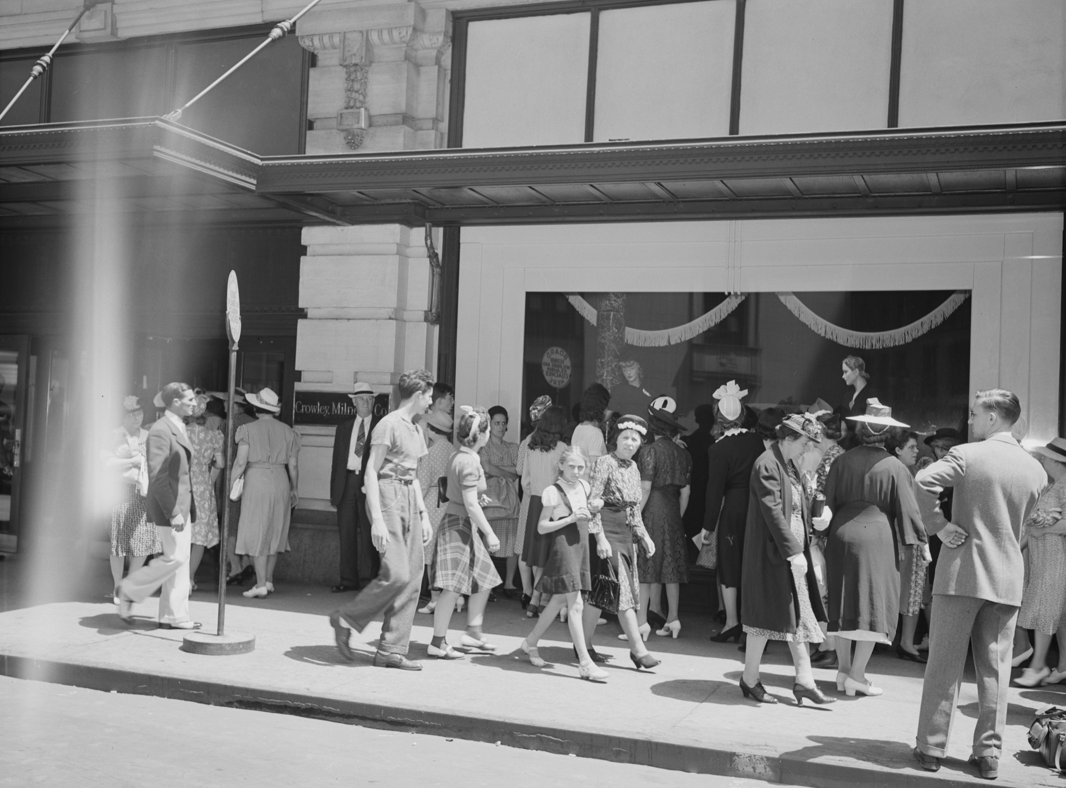 Crowds on the sidewalk in front of a department store.